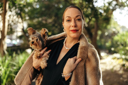 Elegant woman looking at the camera while holding her puppy