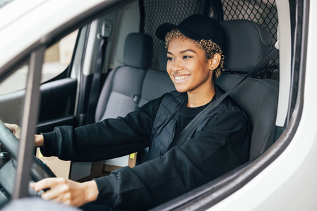 Portrait of a young woman working for a delivery service  sitting on a drivers seat