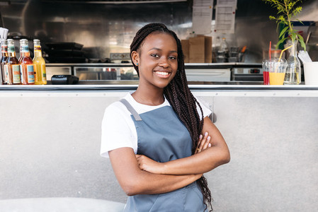 Portrait of a confident waitress with long braids standing at food truck