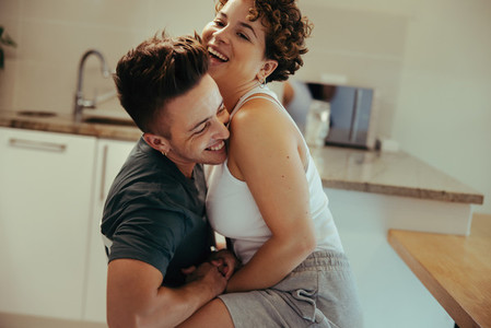 Romantic queer couple laughing in the kitchen