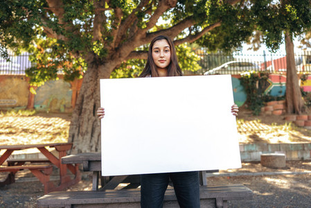 Teenage activist holding a blank placard outdoors in the city