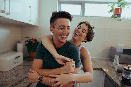 Romantic queer couple laughing together in their kitchen
