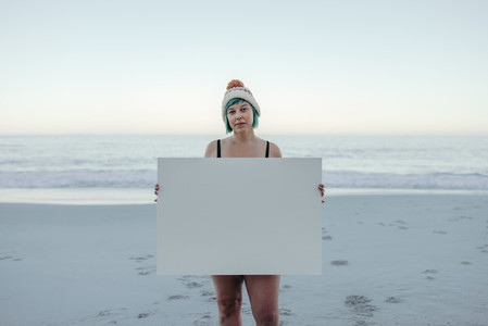 Confident winter bather holding a placard at the beach
