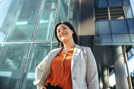 Cheerful businesswoman standing in front of an office building