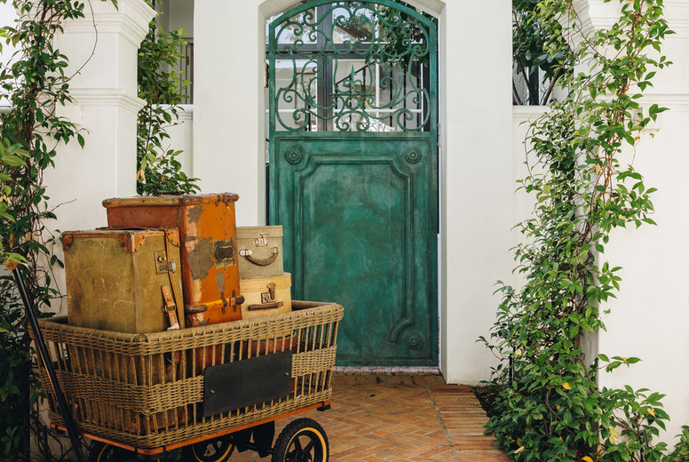Trolley cart full of vacation bags in front of a hotel entrance