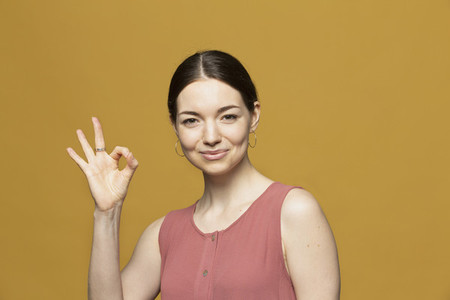Portrait happy young woman gesturing OK