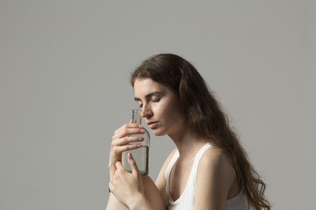 Serene young woman holding bottle of water