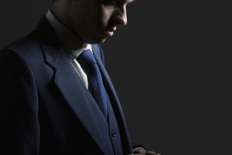 Businessman in suit texting with smart phone on black background