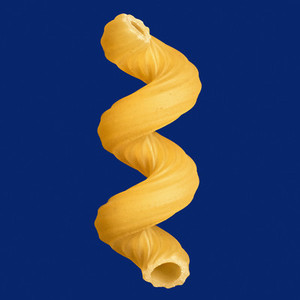 Close up uncooked fusilli pasta noodle on blue background