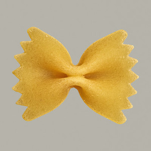 Close up uncooked farfalle bowtie pasta on gray background