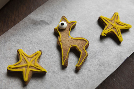 Decorated gingerbread reindeer and stars on parchment paper