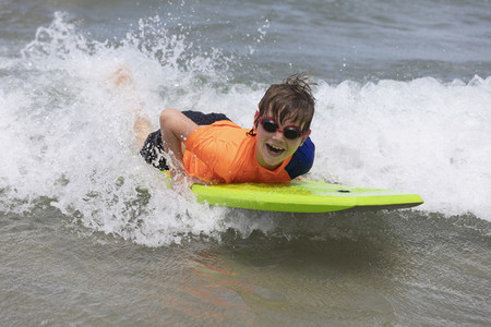 Portrait happy boy bodyboarding in ocean
