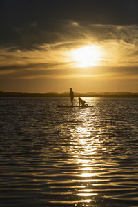 Mother and son paddle boarding on tranquil sunset ocean