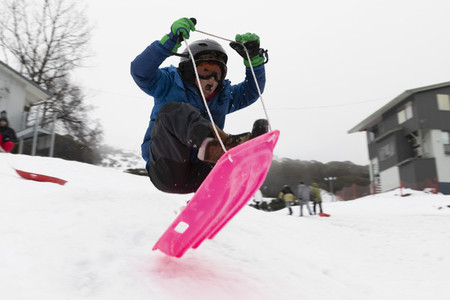 Boy sledding on snowy slope