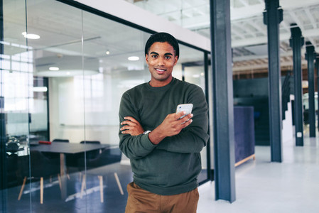 Creative young businessman holding a smartphone in a modern office