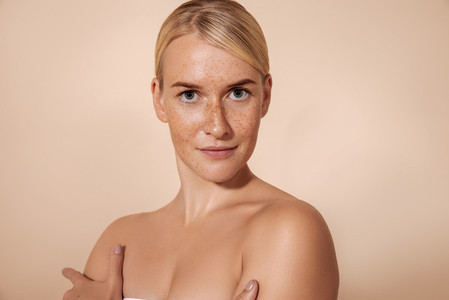 Young woman with perfect skin with freckles posing in studio and looking at camera
