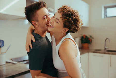 Queer couple laughing cheerfully in the kitchen