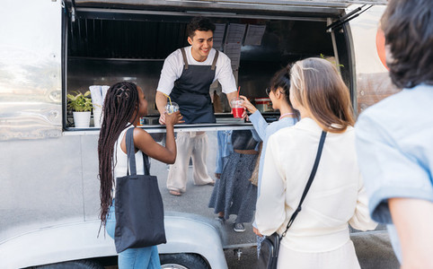 Queue of people to the food truck  Smiling salesman gives drinks to customers