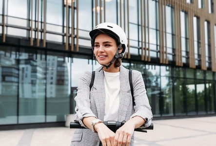 Beautiful smiling woman wearing cycling helmet looking away while standing in the city