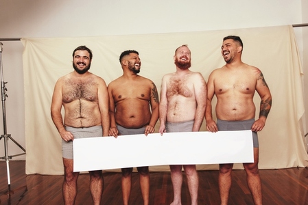 Cheerful body positivity activists holding a white banner