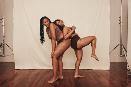 Two happy female friends being playful in a studio