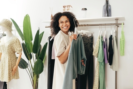 Laughing woman customer choosing sweatshirt in a small boutique