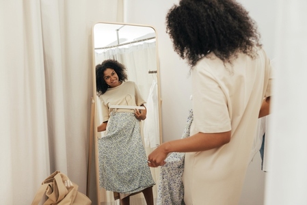 Stylish woman trying on clothes in a dressing room in a boutique