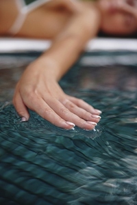 Female hand touching the water surface in a pool