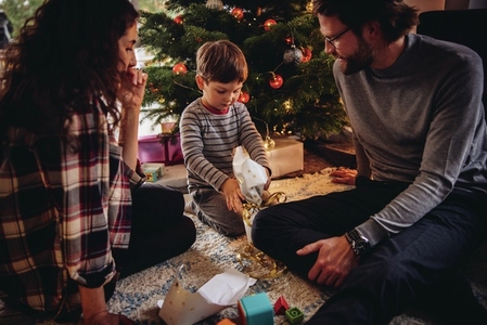 Boy opening his Christmas gift with parents