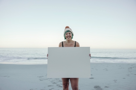 Self confident winter bather holding a blan placard at the beach
