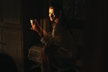 Brunette woman having coffee in the dark