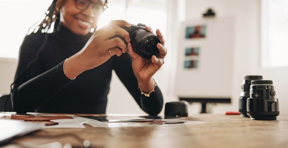 Woman holding a dslr camera in her home office