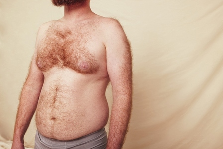 Hairy man with a pot belly standing in a studio