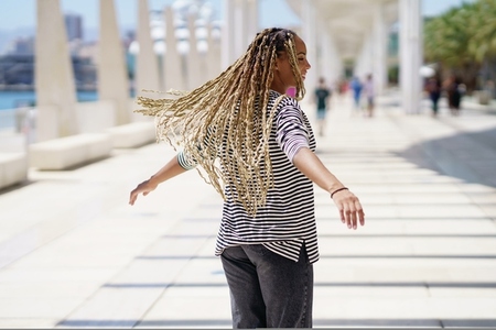 Young black female moving her coloured braids in the wind  Typical African hairstyle