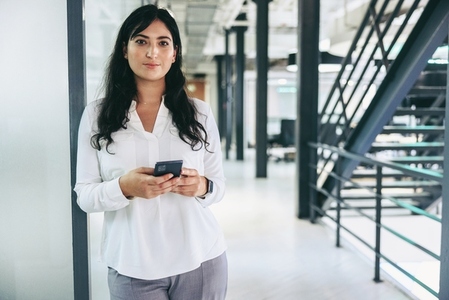 Smart businesswoman holding a smartphone in an office