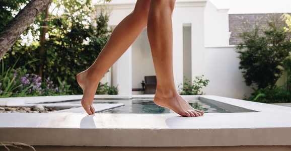 Female legs walking beside a pool