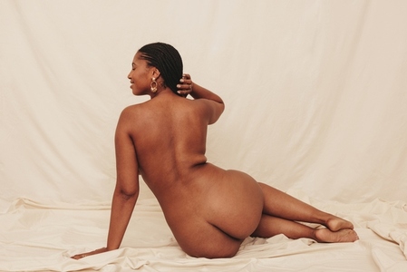 Happy young woman posing nude in a studio