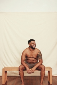 Shirtless young man laughing cheerfully in a studio