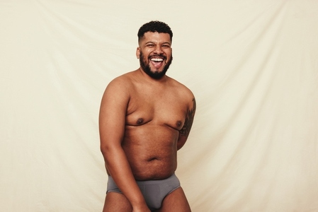 Confident young man laughing cheerfully in underwear