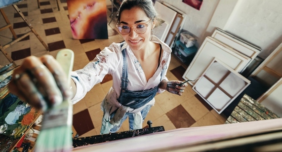 Cheerful artist painting on a canvas in her studio