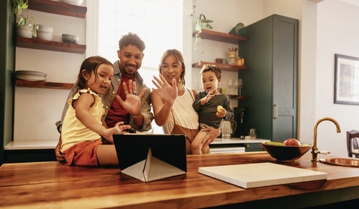 Happy family waving at a tablet during a video call