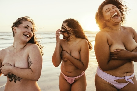 Topless women laughing cheerfully at the beach