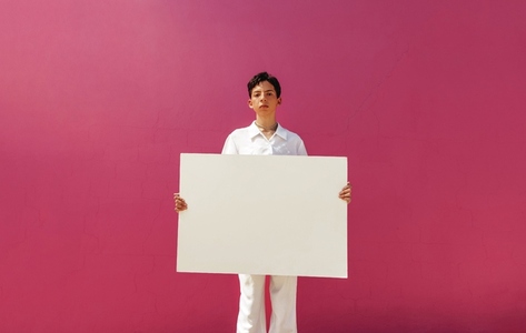 Young queer activist holding a white banner against a pink background