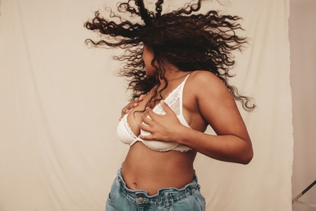 Young woman whipping her hair and embracing her body