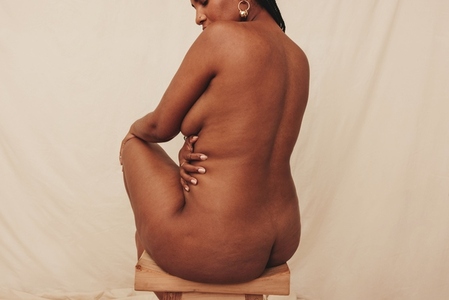 Woman embracing her nude body in a studio