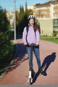 Young woman in her twenties riding an electric scooter using helmet