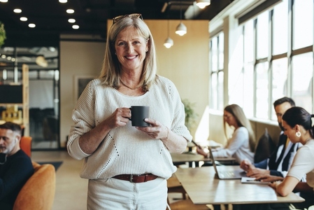 Smiling mature businesswoman standing in a co working space