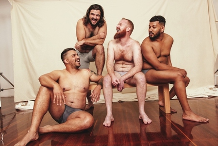 Group of shirtless men laughing and having fun in a studio