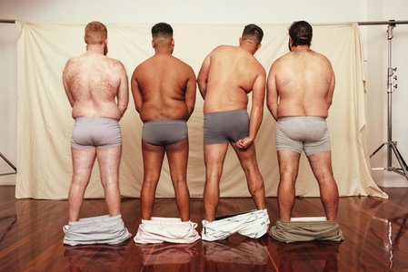 Group of shirtless men standing with their shorts dropped down