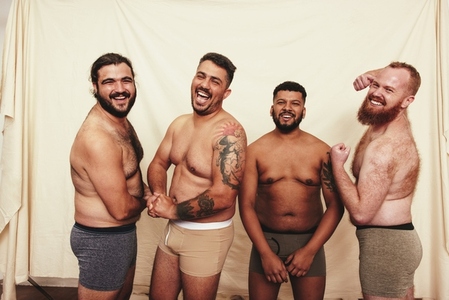 Cheerful men flexing their natural bodies in a studio